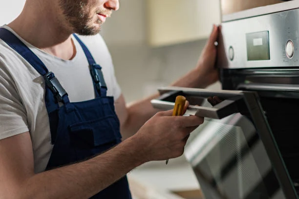 Technician using a screwdriver to service a built-in oven